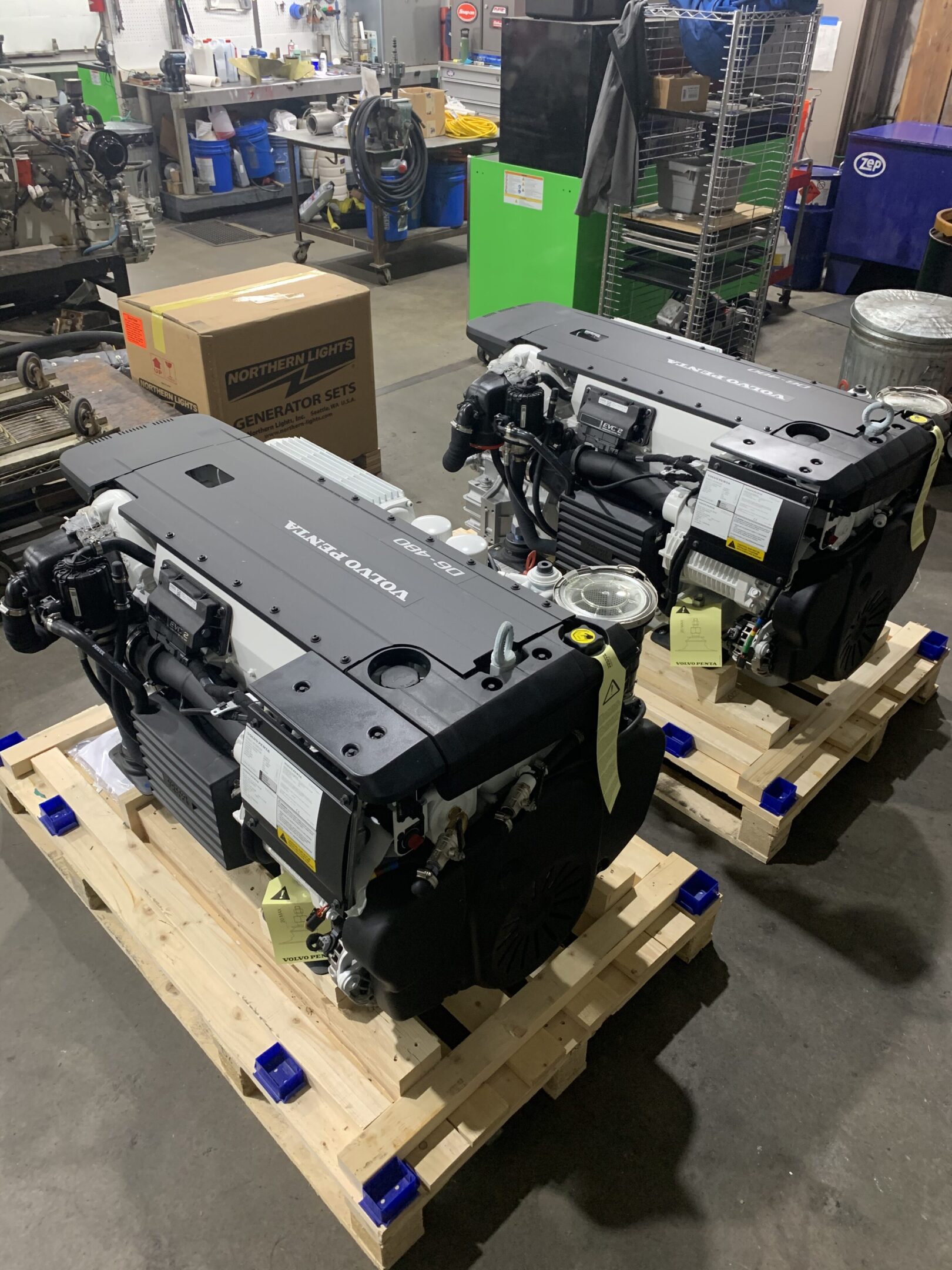 Two large machines are sitting on pallets in a warehouse.